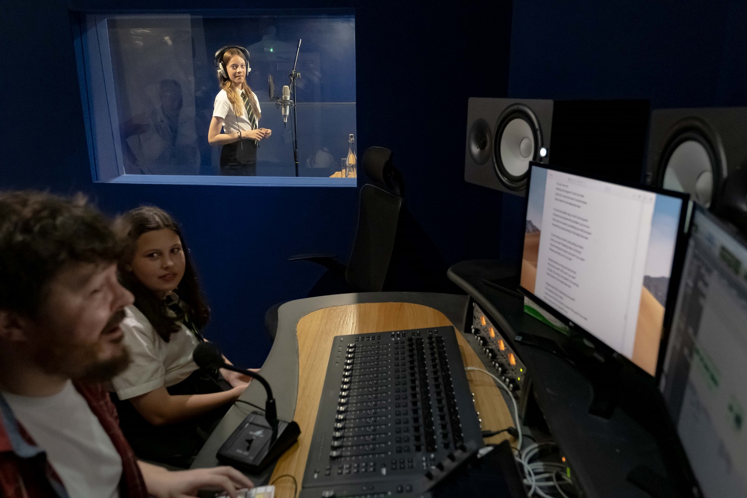 A pupil in a recording booth, one outside at the mixing desk, and an adult in front of a computer
